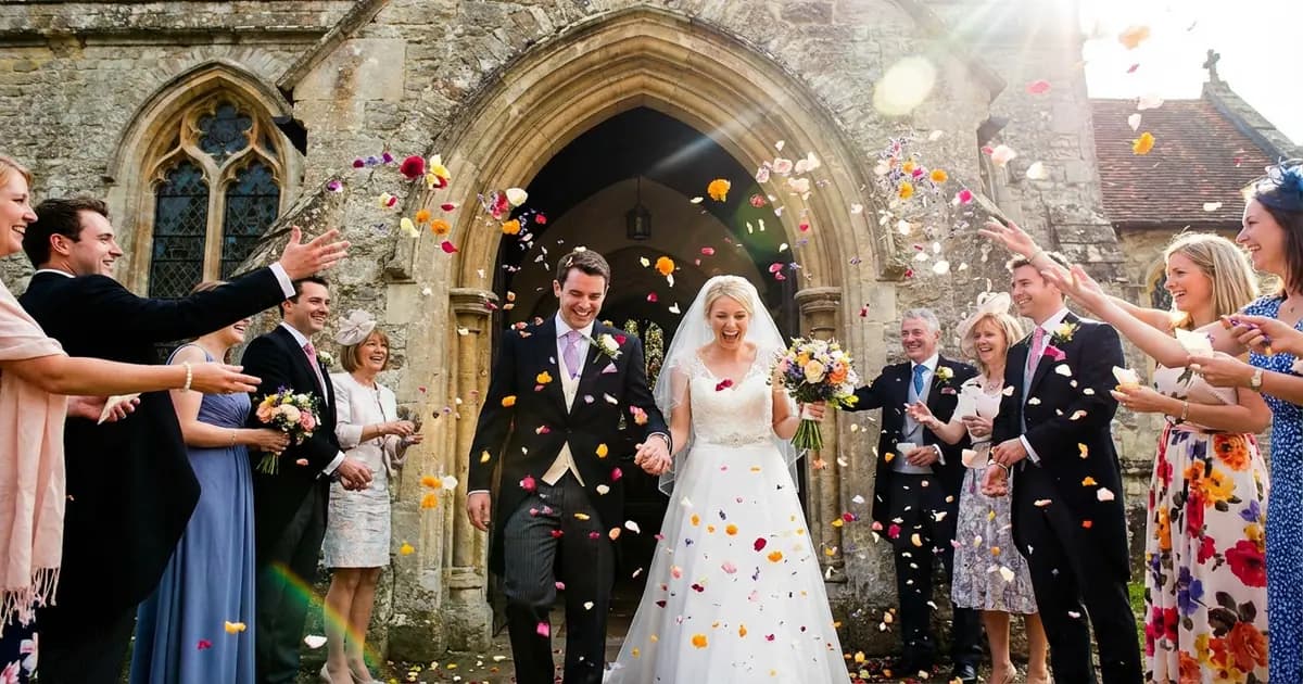 Novios saliendo de la ceremonia mientras los invitados lanzan pétalos de flores y arroz