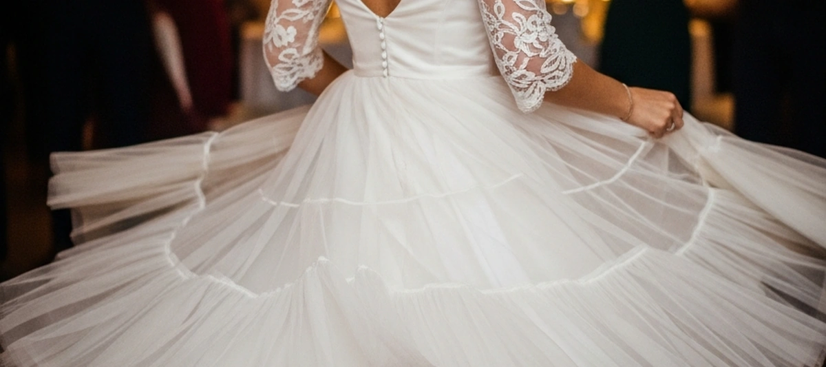 Novia de espaldas bailando con vestido corto de falda circular de tul y seda, tela volando, fiesta de boda con luces bokeh